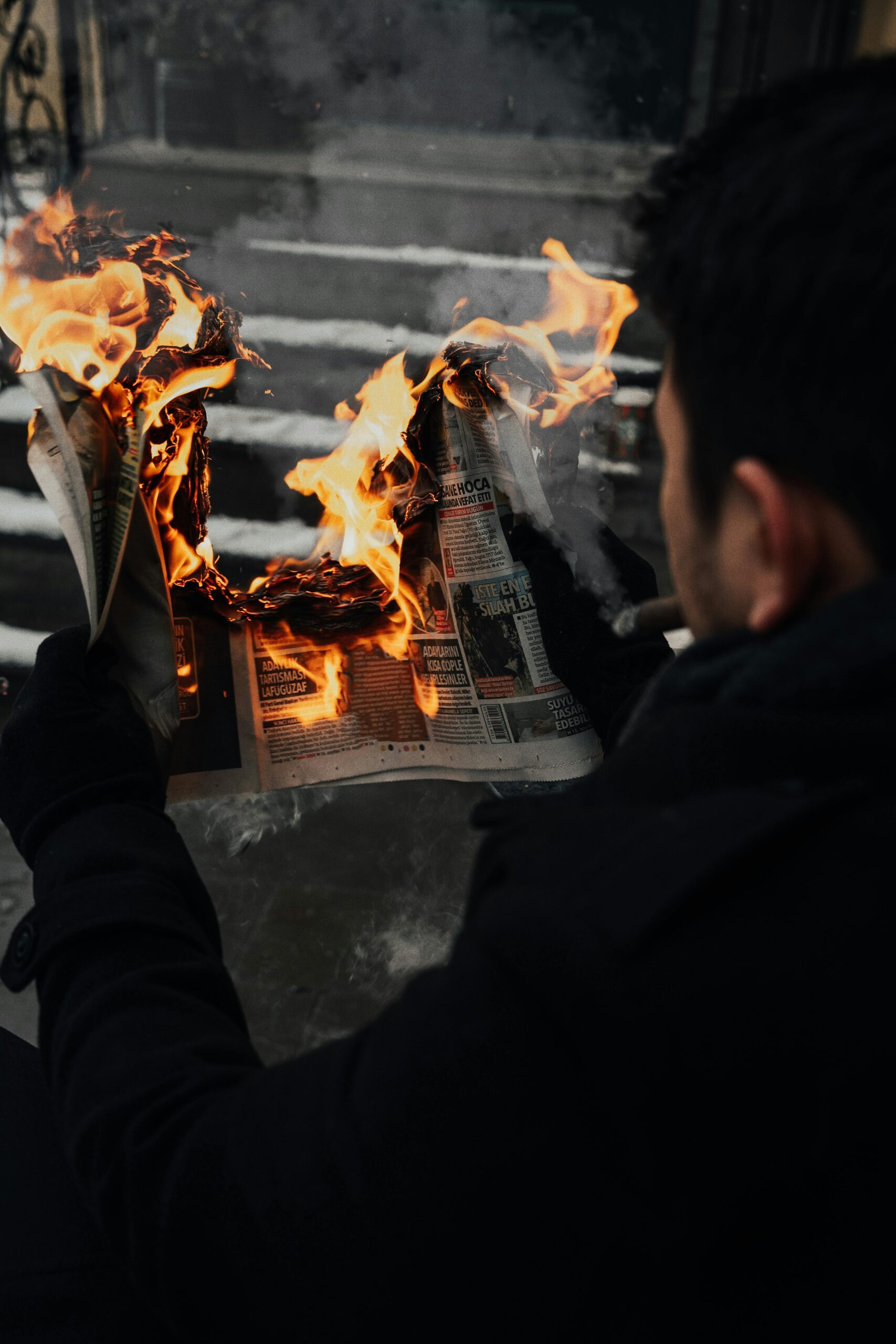 Man holding a newspaper that is on fire